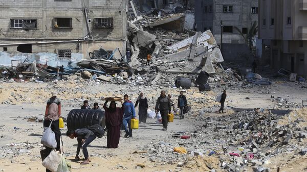 Palestinians walk through the destruction left by the Israeli offensive on Khan Younis, Gaza Strip - Sputnik International