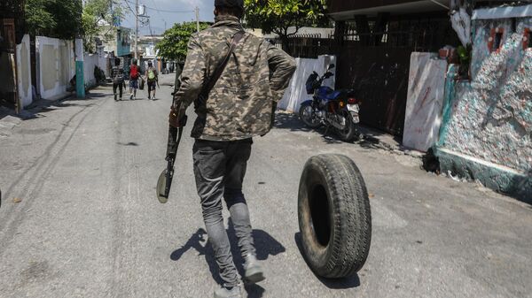An armed member of the G9 and Family gang rolls a tire to burn at a roadblock in the Delmas 6 neighborhood of Port-au-Prince, Haiti, Monday, March 11, 2024 - Sputnik International