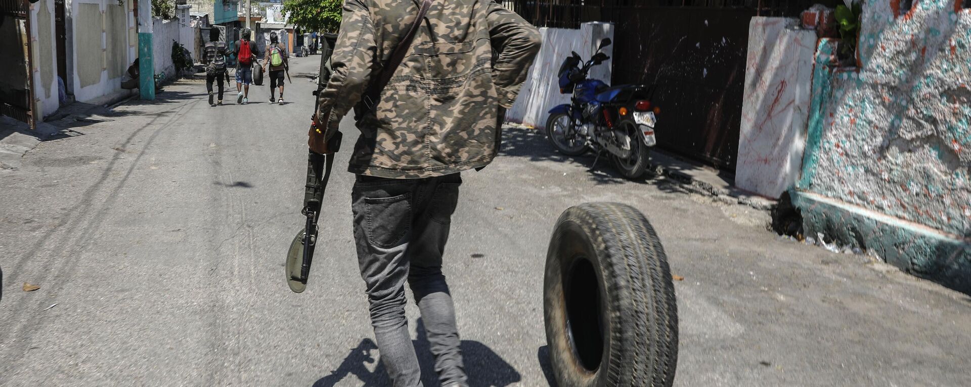 An armed member of the G9 and Family gang rolls a tire to burn at a roadblock in the Delmas 6 neighborhood of Port-au-Prince, Haiti, Monday, March 11, 2024 - Sputnik International, 1920, 12.03.2024