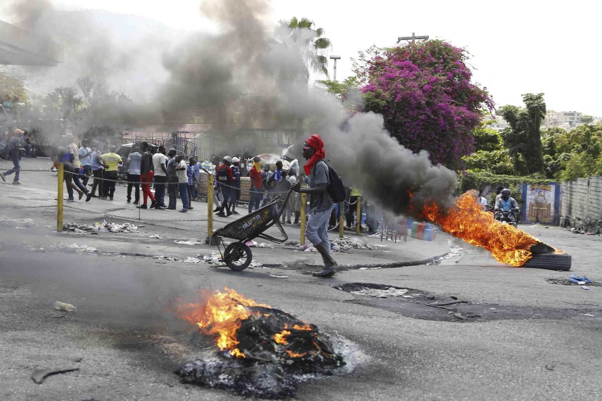 A man pushes a wheelbarrow past burning tires during a protest demanding the resignation of Prime Minister Ariel Henry, in Port-au-Prince, Haiti, Thursday, March 7, 2024. - Sputnik International, 1920, 12.03.2024