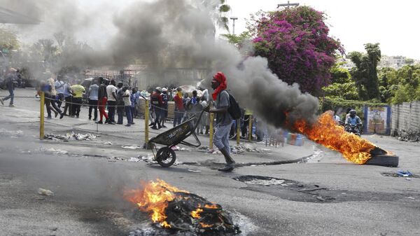 A man pushes a wheelbarrow past burning tires during a protest demanding the resignation of Prime Minister Ariel Henry, in Port-au-Prince, Haiti, Thursday, March 7, 2024. - Sputnik International
