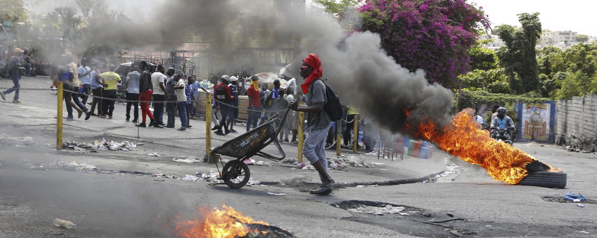 A man pushes a wheelbarrow past burning tires during a protest demanding the resignation of Prime Minister Ariel Henry, in Port-au-Prince, Haiti, Thursday, March 7, 2024. - Sputnik International, 1920, 21.05.2024