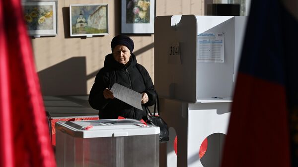 A woman votes for the President of Russia at an electoral precinct in Moscow - Sputnik International