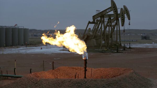 Oil pump jacks work behind a natural gas flare, Wednesday, Dec. 17, 2014, near Watford City, N.D - Sputnik International