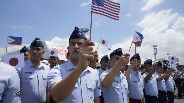Сотрудники филиппинской береговой охраны размахивают маленькими флагами Филиппин, США и Японии на трехсторонних учениях береговой охраны трех стран, которые будут проведены вблизи Южно-Китайского моря - Sputnik International