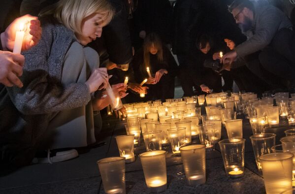People lighting candles in memory of the victims of the heinous terrorist attack. - Sputnik International