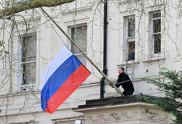 A person adjusts the Russian national flag to fly at half-mast on the building of the Russian Embassy in London.  - Sputnik International