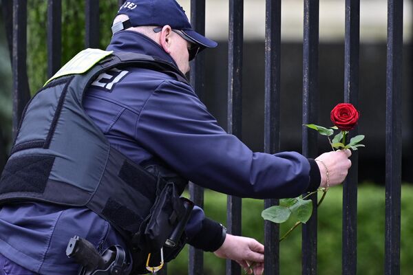 A police officer lays flower outside the Russian Embassy in Berlin.  - Sputnik International