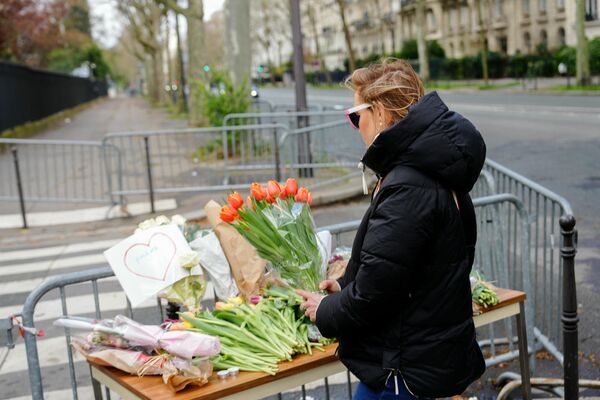 A woman holds a bunch of flowers at a makeshift memorial in front of Russia&#x27;s Embassy in Paris.  - Sputnik International