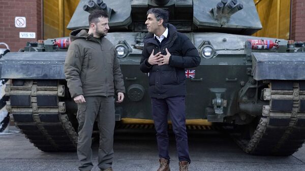 Ukraine's President Volodymyr Zelensky (L) listens to Britain's Prime Minister Rishi Sunak as they wait to meet Ukrainian troops being trained to command Challenger 2 tanks at a military facility in Lulworth, Dorset in southern England on February 8, 2023.  - Sputnik International