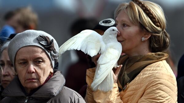 A woman holds a white dove during a requiem liturgy for the victims of the terrorist attack at Crocus City Hall. - Sputnik International