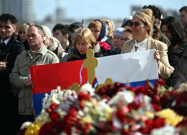 People with a poster colored as the Russian and Serbian flags stand by the memorial in the Moscow region. - Sputnik International