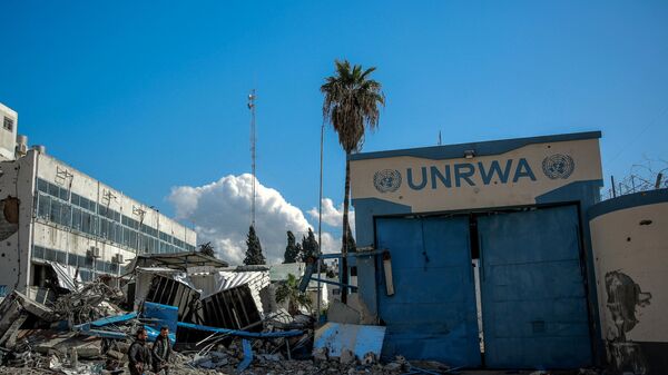 People walk past the damaged Gaza City headquarters of the United Nations Relief and Works Agency for Palestine Refugees (UNRWA) on February 15, 2024, amid ongoing battles between Israel and the militant group Hamas. - Sputnik International