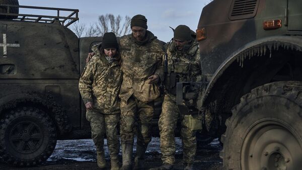 Military medics help a Ukrainian soldier wounded in a battle to get into an evacuation vehicle near Artyomovsk. File photo - Sputnik International