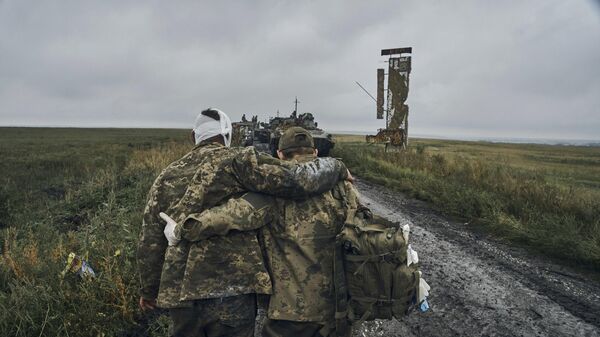 A Ukrainian soldier helps a wounded fellow. File photo - Sputnik International