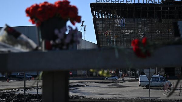 Flowers and toys are placed on the roadside in front of the burnt-out Crocus City Hall following a terrorist attack on the concert venue in Moscow Region, Russia. - Sputnik International
