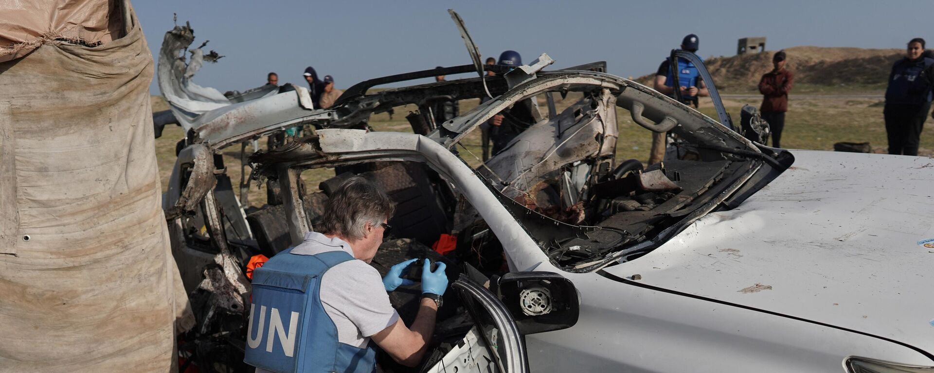 United Nations staff members inspect the carcass of a car used by US-based aid group World Central Kitchen, that was hit by an Israeli strike the previous day in Deir al-Balah in the central Gaza Strip on April 2, 2024. - Sputnik International, 1920, 03.04.2024