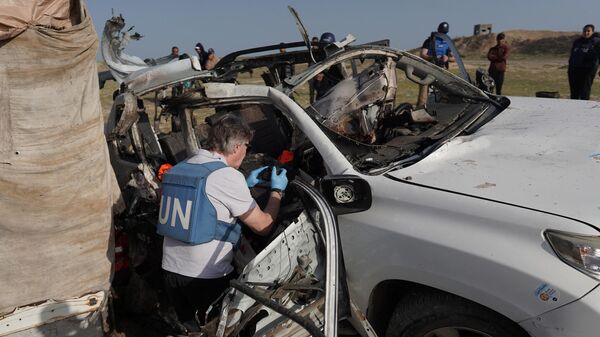 United Nations staff members inspect the carcass of a car used by US-based aid group World Central Kitchen, that was hit by an Israeli strike the previous day in Deir al-Balah in the central Gaza Strip on April 2, 2024. - Sputnik International