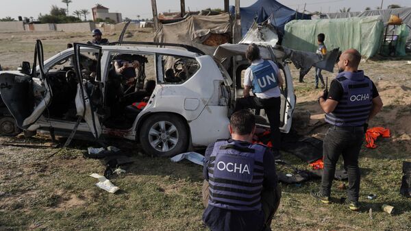 United Nations staff members inspect the carcass of a car used by US-based aid group World Central Kitchen, that was hit by an Israeli strike the previous day in Deir al-Balah in the central Gaza Strip on April 2, 2024. - Sputnik International