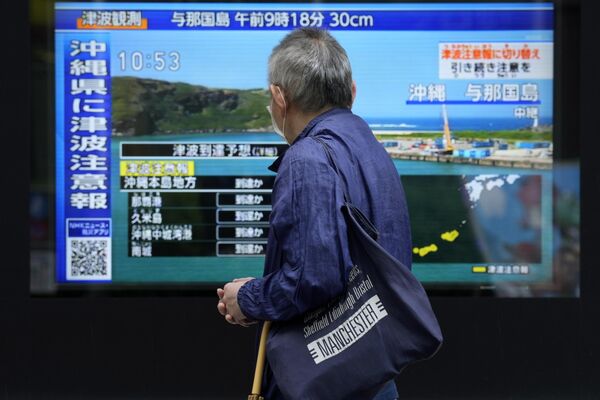 A person stands along a sidewalk to watch a TV showing a breaking news on tsunami for Okinawa region in Tokyo. Japan issued tsunami alerts on Wednesday after a strong quake near Taiwan. (AP Photo/Eugene Hoshiko) - Sputnik International