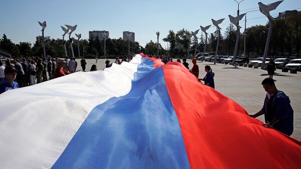 People hold a giant Russian flag during celebrations of the Russia's National Flag Day - Sputnik International