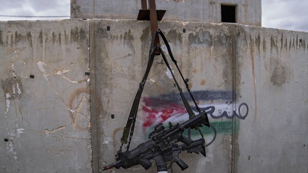 Two M-16 rifles hanging on a wall with a graffiti featuring the Palestinian flag at the IDF Urban Warfare Training Center at the Zeelim army base, southern Israel - Sputnik International