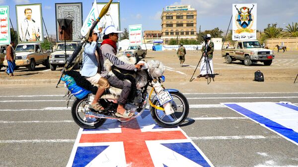 Armed Yemeni men drive a motorcycle over a British and an Israeli flag painted on the asphalt in the Houthi-run capital Sanaa, during a march in support of the Palestinians amid ongoing battles between Israel and Hamas militants in the Gaza Strip, on February 29, 2024. - Sputnik International