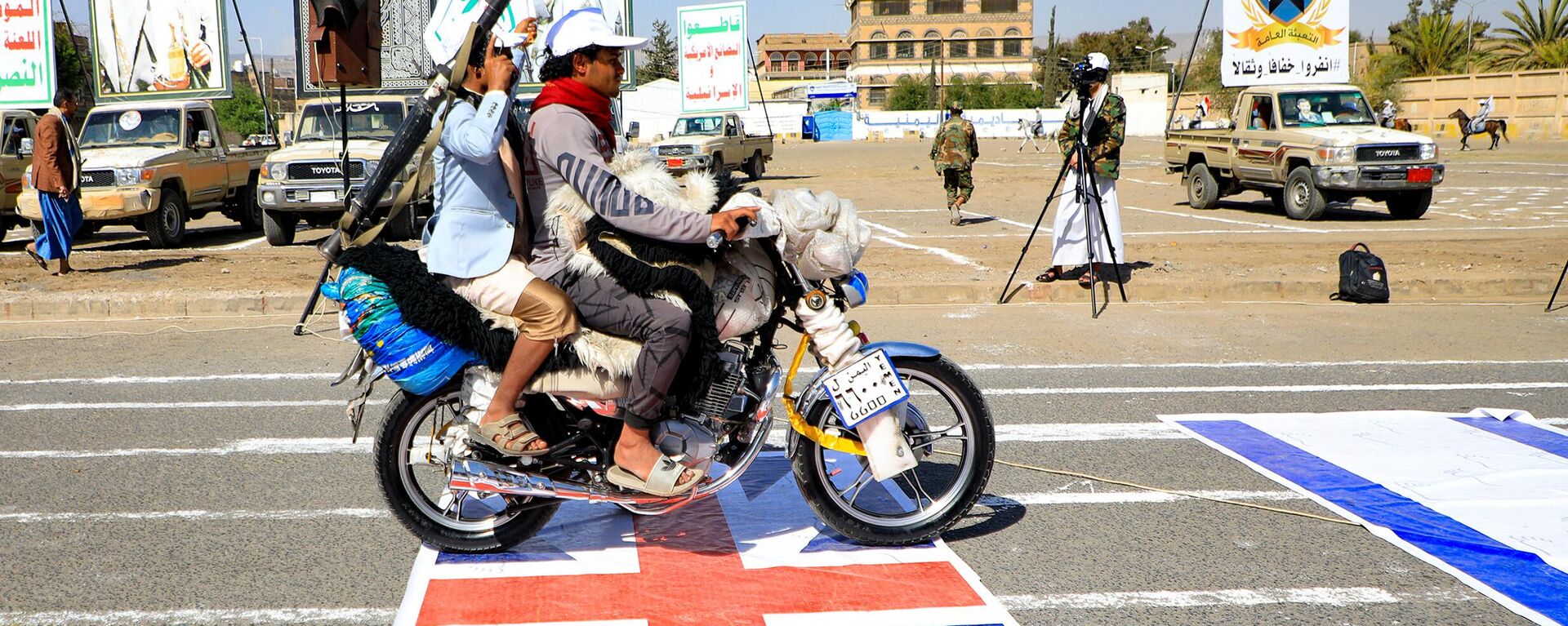 Armed Yemeni men drive a motorcycle over a British and an Israeli flag painted on the asphalt in the Houthi-run capital Sanaa, during a march in support of the Palestinians amid ongoing battles between Israel and Hamas militants in the Gaza Strip, on February 29, 2024. - Sputnik International, 1920, 06.04.2024