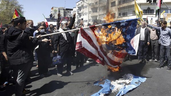 Iranian demonstrators burn representations of the US and Israeli flags during an annual rally to mark Quds Day, or Jerusalem Day, in support of Palestinians, in Tehran, Iran, Friday, April 5, 2024. In the rally in Tehran, thousands attended a funeral procession for the seven Revolutionary Guard members killed in an airstrike widely attributed to Israel that destroyed Iran's Consulate in the Syrian capital on Monday. (AP Photo/Vahid Salemi) - Sputnik International
