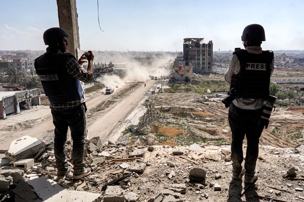 Journalists film atop a damaged building facing the ravaged building of Al-Salam Hospital. - Sputnik International