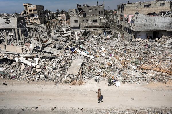 A man walks past the rubble of a local building. - Sputnik International