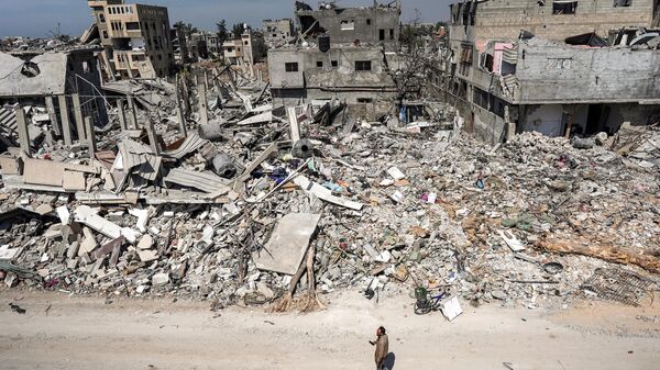 A man walks past the rubble of a destroyed building in Khan Yunis - Sputnik International