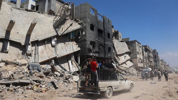 Palestinians use a road in front of damaged buildings in Khan Yunis - Sputnik International