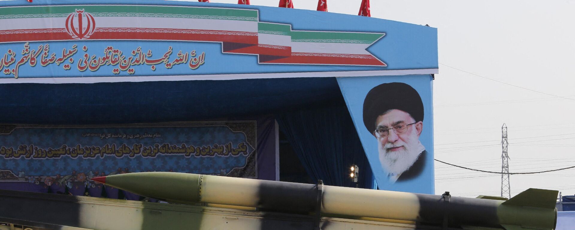 یک کامیون نظامی ایرانی، موشک‌هایی را از کنار تصویر آیت‌الله علی خامنه‌ای رهبر ایران در مراسم رژه روز ارتش این کشور در 18 آوریل 2018 در تهران حمل می‌کند.  - اسپوتنیک بین المللی، 1920، 2024/04/17