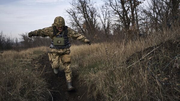 A Ukrainian soldier runs for cover during fights with Russian forces near Maryinka, Ukraine, Friday, Dec. 23, 2022. - Sputnik International