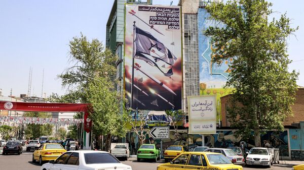 Vehicles drive past a building showing a banner depicting missiles and drones flying past a torn Israeli flag, with text in Persian reading the next slap will be harder and in Hebrew your next mistake will be the end of your fake state, in Palestine Square in Tehran on April 14, 2024. - Sputnik International