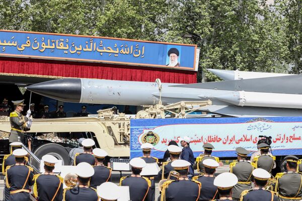 A member of the Iranian Armed Forces leads an army orchestra while a combat vehicle transports a missile. - Sputnik International