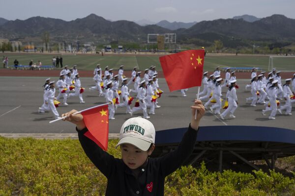 A child holds up Chinese national flags as sailors run past at the Chinese People&#x27;s Liberation Army’s (PLA) naval submarine academy during a tour arranged for foreign journalists. - Sputnik International