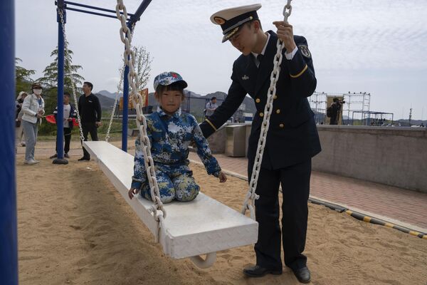 A Navy officer attends to a child wearing a naval camouflage uniform. - Sputnik International