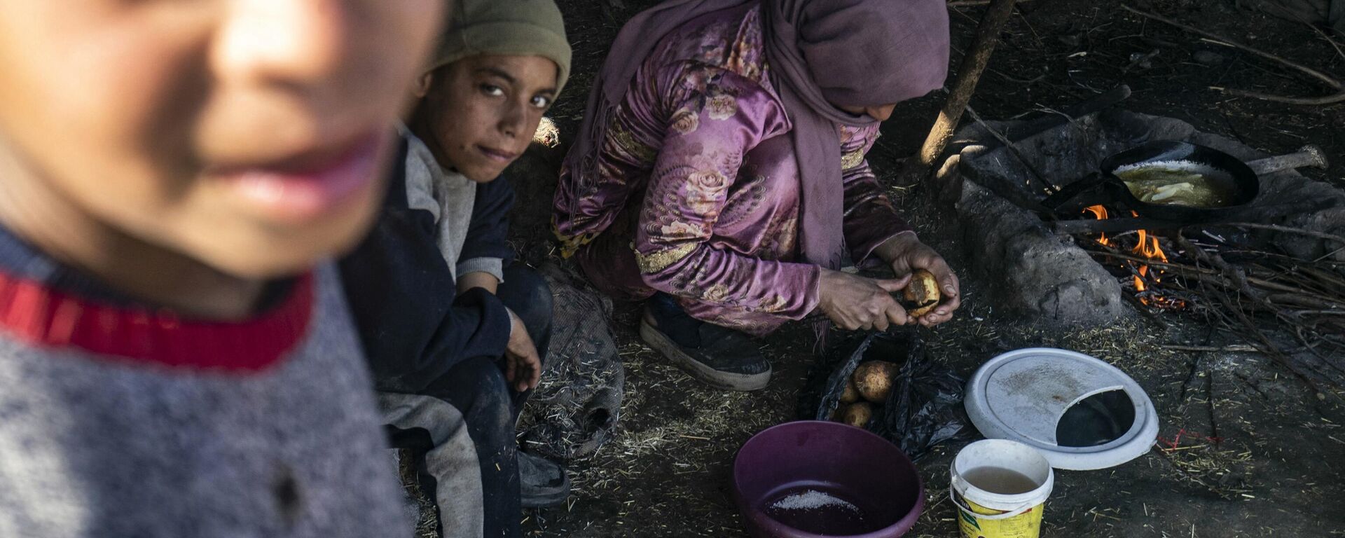 A displaced Syrian woman uses wood twigs for cooking as children look on, at the Al-Younani camp on the outskirts of the northern city of Raqa, amid a shortage of fuel and gas, on February 8, 2024. - Sputnik International, 1920, 22.04.2024