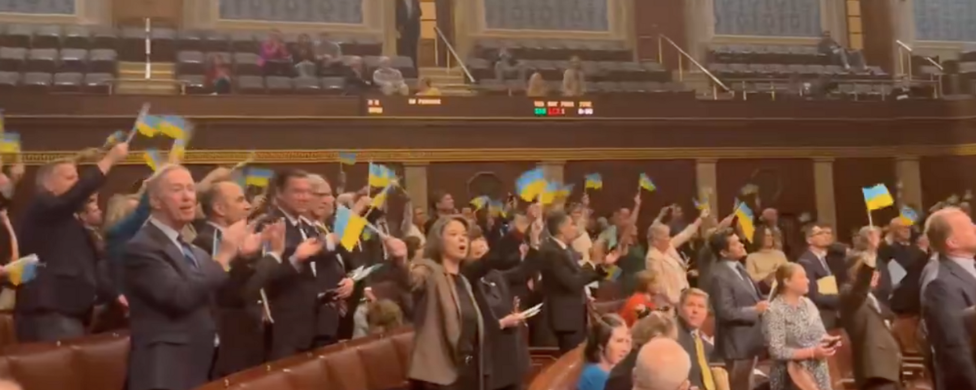 تصویری از ویدئویی که توسط نماینده توماس ماسی (R-KY) در پلتفرم رسانه اجتماعی X منتشر شده است، اعضای مجلس نمایندگان ایالات متحده را نشان می دهد که پرچم های اوکراین را پس از تصویب لایحه کمک های نظامی گسترده به این کشور به اهتزاز در می آورند.  - اسپوتنیک بین المللی، 1920، 2024/04/24