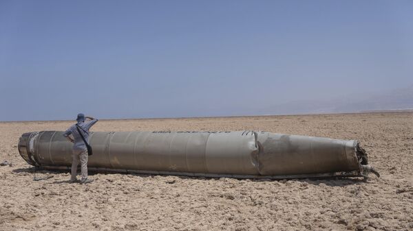 A photojournalist looks at part of the intercepted ballistic missile that fell near the Dead Sea - Sputnik International