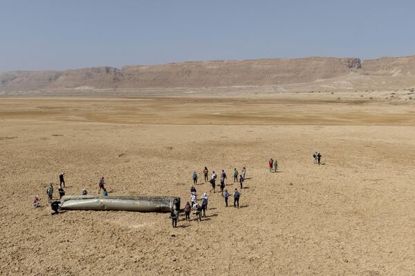ساکنان محلی اطراف یکی از اجزای یک موشک بالستیک ایرانی که توسط پدافند هوایی اسرائیل رهگیری شده است، جمع شده اند.  - اسپوتنیک بین المللی