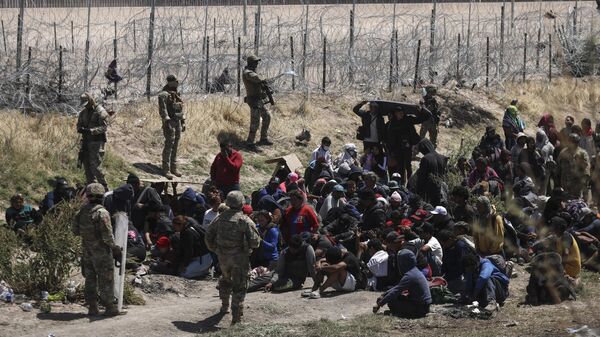 Migrants of different nationalities pray in front of anti-riot agents of the Texas National Guard who prevent passage towards their border line, as seen from Ciudad Juarez, state of Chihuahua, Mexico, on April 16, 2024.  - Sputnik International