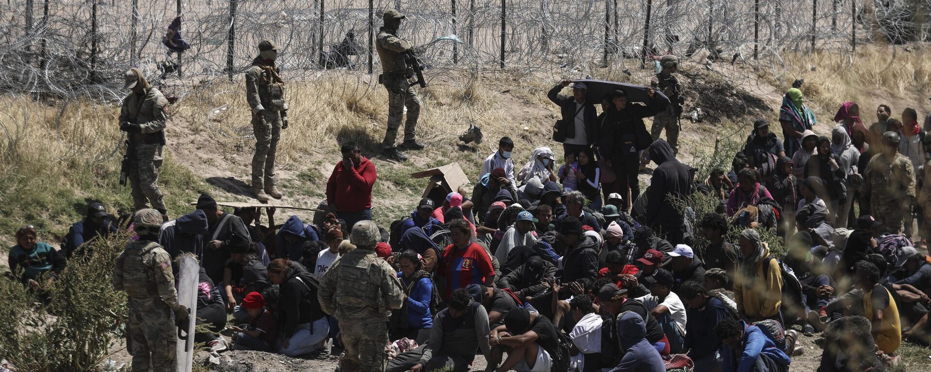 Migrants of different nationalities pray in front of anti-riot agents of the Texas National Guard who prevent passage towards their border line, as seen from Ciudad Juarez, state of Chihuahua, Mexico, on April 16, 2024.  - Sputnik International, 1920, 26.04.2024