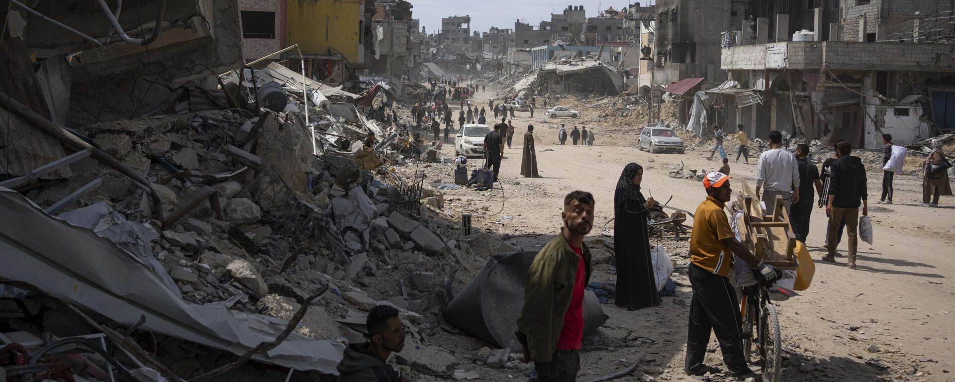 Palestinians walk through the destruction in the wake of an Israeli air and ground offensive in Khan Younis, southern Gaza Strip, Monday, April 8, 2024 - Sputnik International, 1920, 26.04.2024
