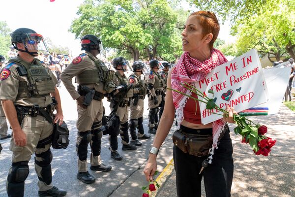 A demonstrator walks past Texas State troopers patrol as pro-Palestinian students rally at the University of Texas in Austin, Texas (April 29, 2024). - Sputnik International