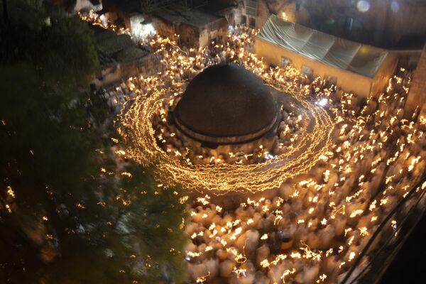 زائران ارتدکس اتیوپیایی در مراسم روشن کردن آتش مقدس در صومعه دیرالسلطان بر روی سقف کلیسای مقبره مقدس در شهر قدیمی اورشلیم پیش از عید پاک ارتدکس شمع می گیرند.  - اسپوتنیک بین المللی