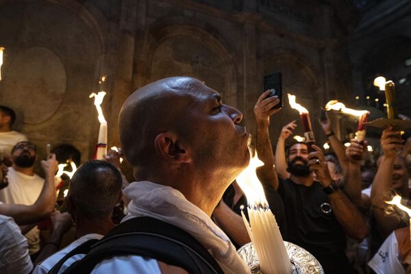 Orthodox Christians gather with lit candles during the Holy Fire ceremony at the Holy Sepulchre Church in Jerusalem&#x27;s Old City on the eve of Easter Sunday. - Sputnik International
