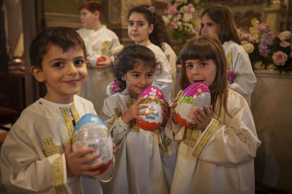 کودکان جامعه ارمنی در رومانی تخم‌های شکلاتی را که در پایان مراسم عید پاک ارتدوکس در کلیسای جامع ارامنه در بخارست دریافت کردند، نگه می‌دارند.  - اسپوتنیک بین المللی